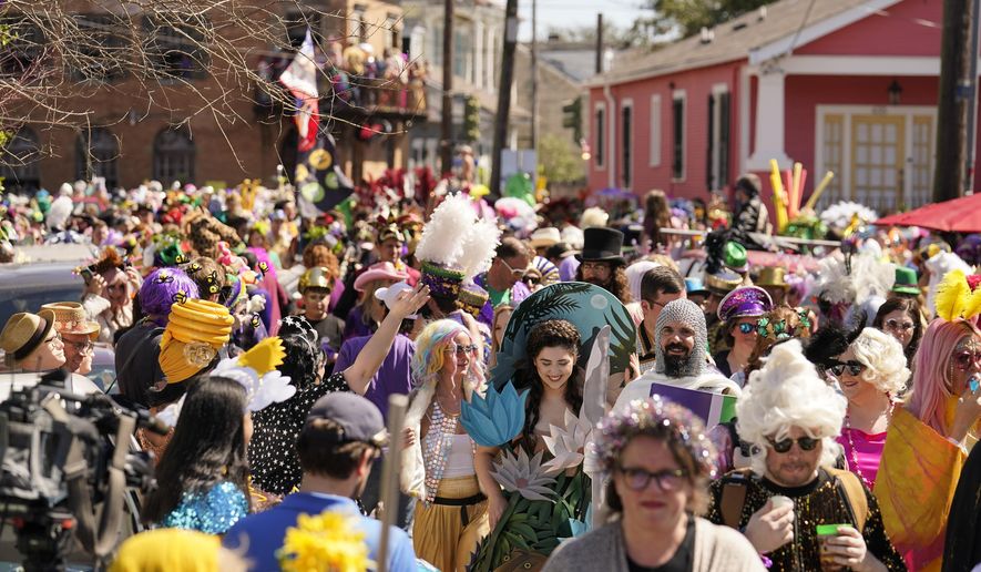 Societe de Sainte Anne parade goers march during Mardi Gras on Tuesday, March 1, 2022, in New Orleans. (AP Photo/Gerald Herbert)