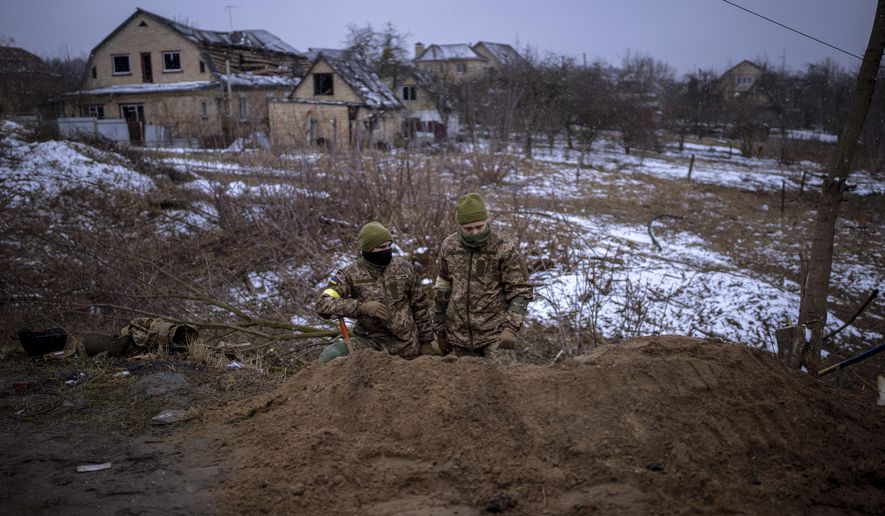 Ukrainian soldiers take positions in a trench on the outskirts of Kyiv, Ukraine, Wednesday, March 2, 2022. Russian forces have escalated their attacks on crowded cities in what Ukraine&#39;s leader called a blatant campaign of terror. (AP Photo/Emilio Morenatti)