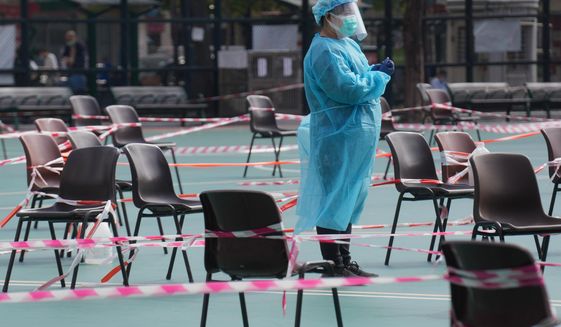 A health worker wearing protective gear waits for residents to be tested for the coronavirus at a temporary testing center in Hong Kong, Monday, Feb. 28, 2022.(AP Photo/Vincent Yu)