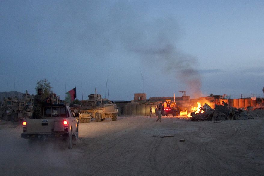 In this April 28, 2011, photo, an Afghan National Army pickup truck passes parked U.S. armored military vehicles, as smoke rises from a fire in a trash burn pit at Forward Operating Base Caferetta Nawzad, Helmand province south of Kabul, Afghanistan. The House is poised to pass legislation that would dramatically boost health care services and disability benefits for veterans exposed to burn pits in Iraq and Afghanistan. (AP Photo/Simon Klingert, File)