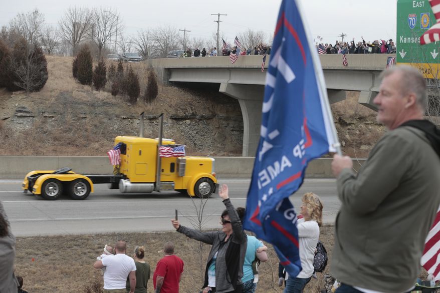 Supporters of the Freedom Convoy wave flags and cheer from the Rice Road overpass in East Topeka, Friday, March 4, 2022, in Topeka, Kan., as truckers head eastward on I-70. (Evert Nelson/The Capital-Journal via AP)