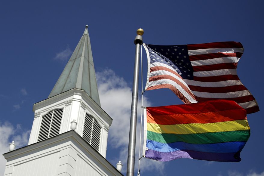 A gay pride rainbow flag flies along with the U.S. flag in front of the Asbury United Methodist Church in Prairie Village, Kan, on April 19, 2019. A group of theologically conservative United Methodists planned to launch a new worldwide denomination on May 1, 2022. This will begin the breakup of the third-largest religious body in the U.S.  (AP Photo/Charlie Riedel, File)