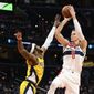 Washington Wizards center Kristaps Porzingis (6) shoots against Indiana Pacers forward Oshae Brissett (12) during the first half of an NBA basketball game, Sunday, March 6, 2022, in Washington. Brissett was charged with a foul on the play. (AP Photo/Nick Wass)