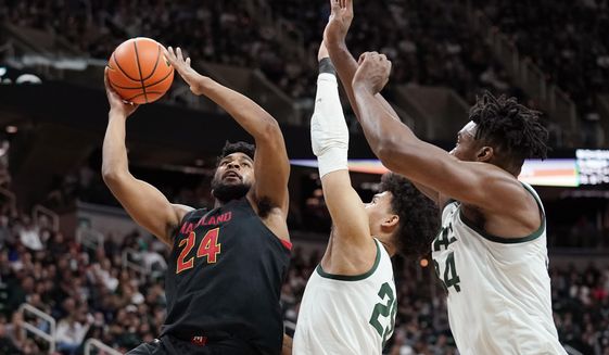 Maryland forward Donta Scott (24) is defended by Michigan State forward Malik Hall, center, and forward Julius Marble II during the first half of an NCAA college basketball game, Sunday, March 6, 2022, in East Lansing, Mich. (AP Photo/Carlos Osorio)