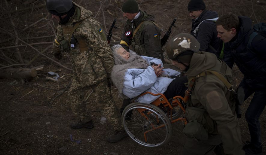 Ukrainian soldiers and militiamen carry a woman in a wheelchair as the artillery echoes nearby, while people flee Irpin on the outskirts of Kyiv, Ukraine, Monday, March 7, 2022. Russia announced yet another cease-fire and a handful of humanitarian corridors to allow civilians to flee Ukraine. Previous such measures have fallen apart and Moscow&#39;s armed forces continued to pummel some Ukrainian cities with rockets Monday. (AP Photo/Emilio Morenatti)