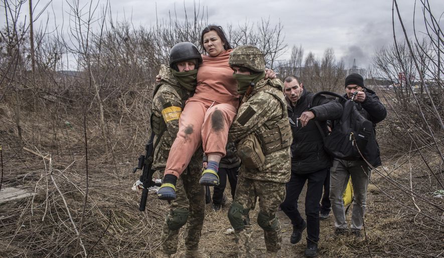 A woman carried by Ukrainian soldiers crosses an improvised path while fleeing the town of Irpin, Ukraine, Sunday, March 6, 2022. In Irpin, near Kyiv, a sea of people on foot and even in wheelbarrows trudged over the remains of a destroyed bridge to cross a river and leave the city. (AP Photo/Oleksandr Ratushniak) **FILE**