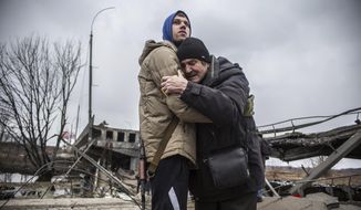 A Ukrainian Territorial Defence Forces member hugs a resident who leaves his home town following Russian artillery shelling in Irpin, on the outskirts of Kyiv, Ukraine, Wednesday, March 9, 2022. (AP Photo/Oleksandr Ratushniak)