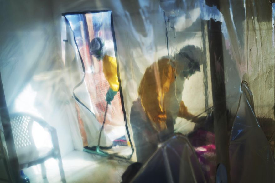 Health workers wearing protective suits tend to to an Ebola victim kept in an isolation tent in Beni, Democratic Republic of Congo, on Saturday, July 13, 2019. (AP Photo/Jerome Delay, File)