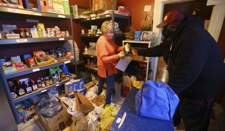 FILE - St. Vincent de Paul food pantry volunteer Deedee Jones helps Ronald Bird gather the food he is receiving for the month on Dec. 8, 2020, in Kokomo, Ind. (Tim Bath/The Kokomo Tribune via AP, File)