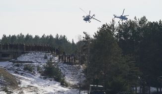U.S. Boeing AH-64 Apache attack helicopters fly over troops during the NATO military exercises Crystal arrow 2022 at the Adazi military range, Latvia, Friday, March 11, 2022. About 2,800 soldiers from Albania, Canada, Czech Republic, Italy, Iceland, Montenegro, Poland, Slovakia, Slovenia, Spain, Latvia and the United States attend the training for interoperability during tactical military operations, including the demonstration of winter capability. (Martins Zilgalvis/F64 via AP)