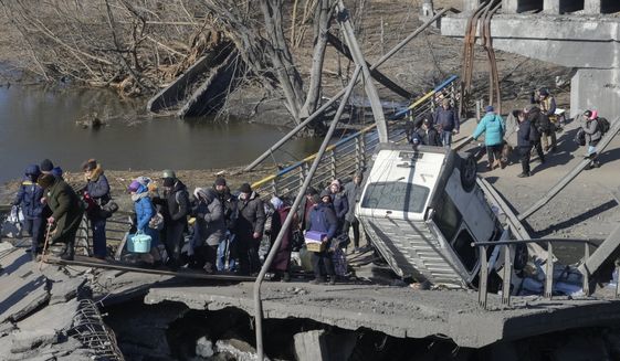 Ukrainians cross an improvised path under a destroyed bridge while fleeing Irpin, some 25 km (16 miles) northwest of Kyiv, Friday, March 11, 2022. Kyiv northwest suburbs such as Irpin and Bucha have been enduring Russian shellfire and bombardments for over a week prompting residents to leave their home. (AP Photo/Efrem Lukatsky)