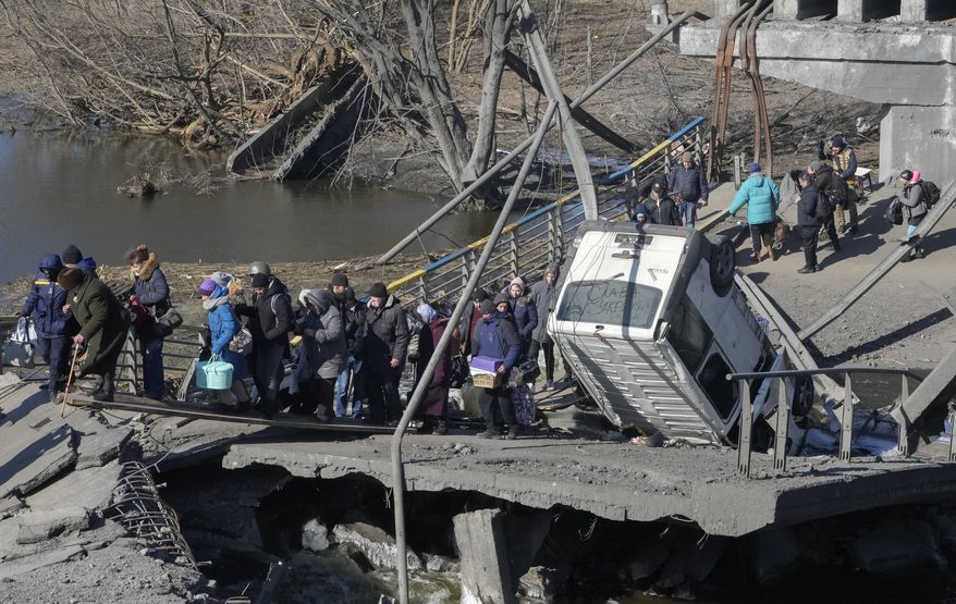 Ukrainians cross an improvised path under a destroyed bridge while fleeing Irpin, some 25 km (16 miles) northwest of Kyiv, Friday, March 11, 2022. Kyiv northwest suburbs such as Irpin and Bucha have been enduring Russian shellfire and bombardments for over a week prompting residents to leave their home. (AP Photo/Efrem Lukatsky)