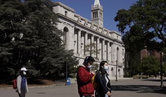 In this March 11, 2020, file photo, people wear masks while walking past Wheeler Hall on the University of California campus in Berkeley, Calif. (AP Photo/Jeff Chiu, File)