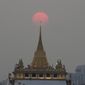 The sun sets behind the golden mount temple in Bangkok, Thailand, Saturday, March 12, 2022. (AP Photo/Sakchai Lalit)