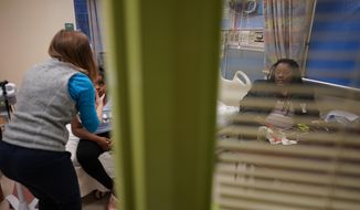 Brooklynn Chiles, 8, is examined during a followup visit at Children&#39;s National Hospital in Washington, Friday, Feb. 11, 2022, as her mother, Danielle Chiles watches at right. Brooklynn&#39;s father, Rodney Chiles, died of COVID-19 last year and she has tested positive three times. Brooklynn is part of a NIH-funded multi-year study at Children&#39;s National Hospital to look at impacts of COVID-19 on children&#39;s physical health and quality of life. (AP Photo/Carolyn Kaster)