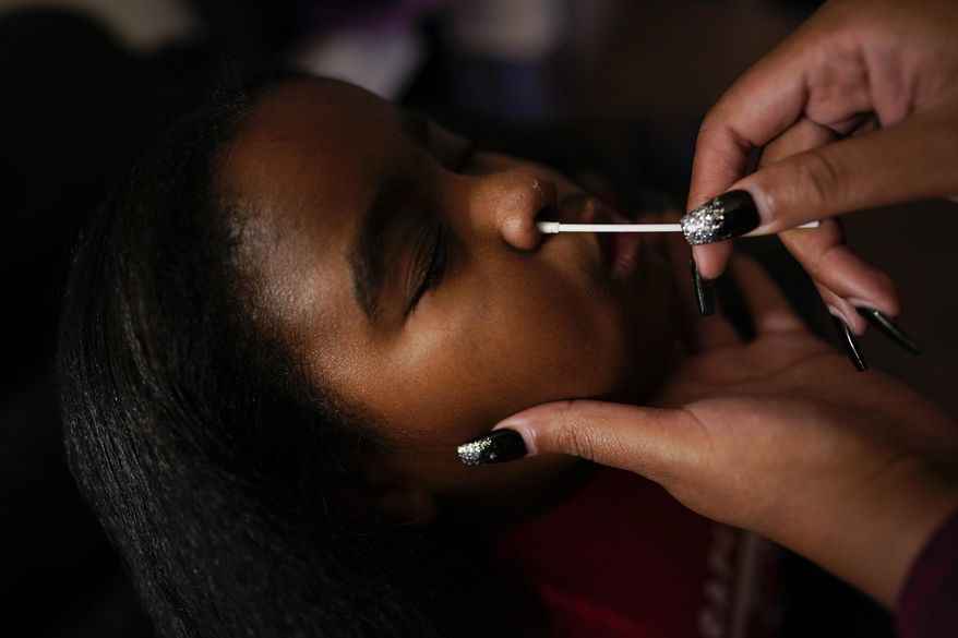 Danielle Chiles gives her daughter, Brooklynn Chiles, 8, a COVID-19 antigen rapid test at home in Washington, Sunday, Jan. 9, 2022. Proof of a negative test is required for Brooklynn to attend third grade classes at Rocketship Rise Academy Public Charter School in Washington. (AP Photo/Carolyn Kaster) **FILE**