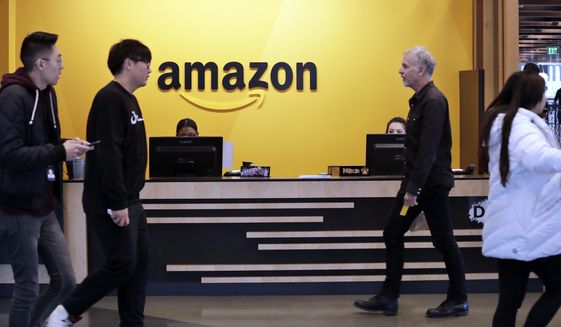 Employees walk through a lobby at Amazon&#39;s headquarters on Nov. 13, 2018, in Seattle.  Amazon said Tuesday, March 15, 2022, it will spend more than $120 million to build affordable-housing units close to transit stations near Seattle and Washington, D.C,  the latest example of a tech company trying to address the affordable housing crisis critics say the industry has exacerbated.(AP Photo/Elaine Thompson, File)