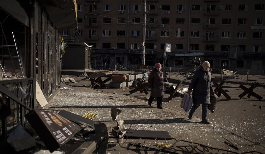 Women walk next to debris of damaged shops after bombing in Kyiv, Ukraine, Tuesday, March 15, 2022. (AP Photo/Felipe Dana)