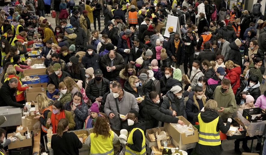 Ukrainian refugees queue for food in the welcome area after their arrival at the main train station in Berlin, Germany, March 8, 2022. The Ukraine war has turned the basement of Berlins glass-and-steel main train station into a sprawling refugee town where a small army of volunteers in yellow and orange vests offer everything from shampoo to cellphone chargers to exhausted refugees. (AP Photo/Michael Sohn, File)