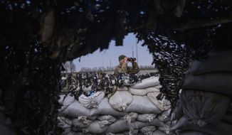A soldier look through binoculars at a military check point, in Lityn, Ukraine, Wednesday, March 16, 2022. (AP Photo/Rodrigo Abd)