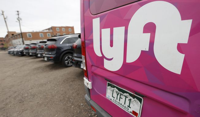 In this April 30, 2020, photo, Kia Neros that are part of the Lyft ride-hailing fleet sit unused in a lot near Empower Field at Mile High in Denver. (AP Photo/David Zalubowski) **FILE**