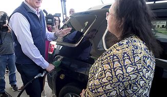 Virginia Gov. Glenn Youngkin,left, pumps gas for Tammy Beard, right, as they discuss the price of gasoline at a BP station on W. Broad St. in Henrico County, Va., Wednesday, March 16, 2022. During a visit to the station, Youngkin said he was sending a bill to the legislature to eliminate the state tax on gasoline for a period of three months. (Bob Brown/Richmond Times-Dispatch via AP)