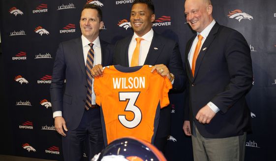 Denver Broncos new starting quarterback Russell Wilson, center, holds up his new jersey for a photograph with head coach Nathaniel Hackett, right, and general manager George Paton during a news conference Wednesday, March 16, 2022, at the team&#39;s headquarters in Englewood, Colo. (AP Photo/David Zalubowski)