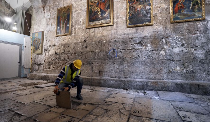A member of the restoration team removes a stone from the floor of the Church of the Holy Sepulchre, where many Christians believe Jesus was crucified, buried and rose from the dead, in the Old City of Jerusalem, Thursday, March 17, 2022. The three Christian communities that have uneasily shared their holiest site for centuries are embarking on a project to restore the ancient stone floor of the Jerusalem basilica. The project includes an excavation that could shed light on the rich history of the Church of the Holy Sepulchre in the Old City. (AP Photo/Mahmoud Illean)