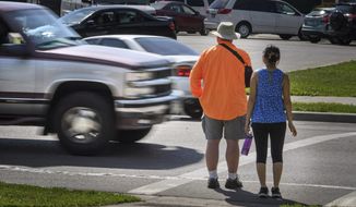 FILE - In this June 8, 2016, file photo, a maroon and silver truck drove, left, drives through the marked crosswalk in front of pedestrian volunteers Dave Passiuk and Nelsie Yang in St. Paul, Minn. Drivers of bigger vehicles such as pickup trucks and SUVs are more likely to hit pedestrians while making turns than drivers of cars, according to a new study. The research released Thursday, March 17, 2022, by the Insurance Institute for Highway Safety points to the increasing popularity of larger vehicles as a possible factor in rising pedestrian deaths on U.S. roads. (Glen Stubbe/Star Tribune via AP, File)