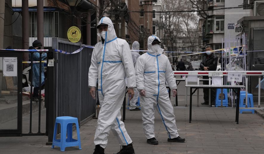 Workers in PPE overalls guard an entrance to a community under lock down on Thursday, March 17, 2022, in Beijing. A fast-spreading variant known as &amp;quot;stealth omicron&amp;quot; is testing China&#x27;s zero-tolerance strategy, which had kept the virus at bay since the deadly initial outbreak in the city of Wuhan in early 2020. (AP Photo/Ng Han Guan)