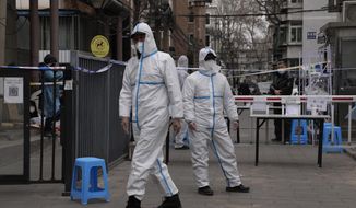 Workers in PPE overalls guard an entrance to a community under lock down on Thursday, March 17, 2022, in Beijing. A fast-spreading variant known as &amp;quot;stealth omicron&amp;quot; is testing China&#39;s zero-tolerance strategy, which had kept the virus at bay since the deadly initial outbreak in the city of Wuhan in early 2020. (AP Photo/Ng Han Guan)