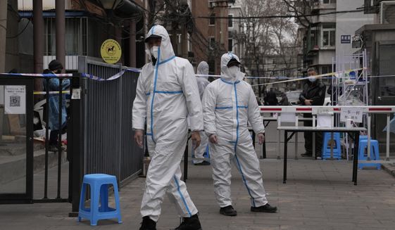 Workers in PPE overalls guard an entrance to a community under lock down on Thursday, March 17, 2022, in Beijing. A fast-spreading variant known as &amp;quot;stealth omicron&amp;quot; is testing China&#39;s zero-tolerance strategy, which had kept the virus at bay since the deadly initial outbreak in the city of Wuhan in early 2020. (AP Photo/Ng Han Guan)