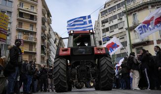 A farmer sits on a tractor with a Greek flag during a protest outside of the Agriculture Ministry in Athens, Greece, on Friday, March 18, 2022. Greek farmers are protesting higher production costs, pressing the center-right government to reduce electricity bills and fuel tax and increase subsidies for animal farms. They gathered outside the ministry of agriculture and were planning to march from there to parliament in central Athens. (AP Photo/Thanassis Stavrakis)