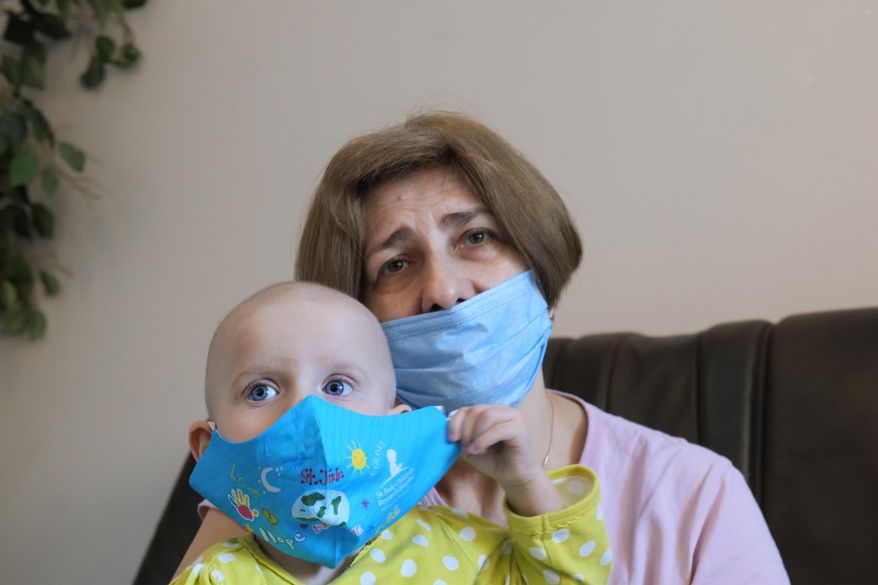 In this file photo, a Ukrainian grandmother holds her 22-month-old granddaughter with leukemia, Yeva Vakulenko, at a clinic in Bocheniec, Poland, on Thursday, March 17, 2022. Vakulenko is among more than 500 Ukrainian children with cancer who have been evacuated so far to a clinic in Poland. They are evaluated by doctors who then decide where they should go next for treatment. Some 200 hospitals in 28 countries are accepting the children. (AP Photo/Pawel Kuczynski)  **FILE**