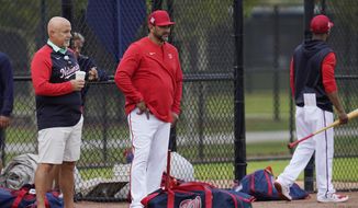 Washington Nationals general manager Mike Rizzo, left, and manager Dave Martinez, center, watch during the team&#39;s spring training baseball workout, Tuesday, March 15, 2022, in West Palm Beach, Fla. (AP Photo/Sue Ogrocki) **FILE**