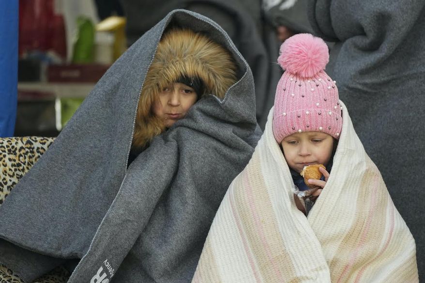 Caption: Ukrainian children covered themselves by blankets have a meal after fleeing the war from neighbouring Ukraine, at the border crossing in Palanca, Moldova, Thursday, March 10, 2022. (AP Photo/Pavel Golovkin)