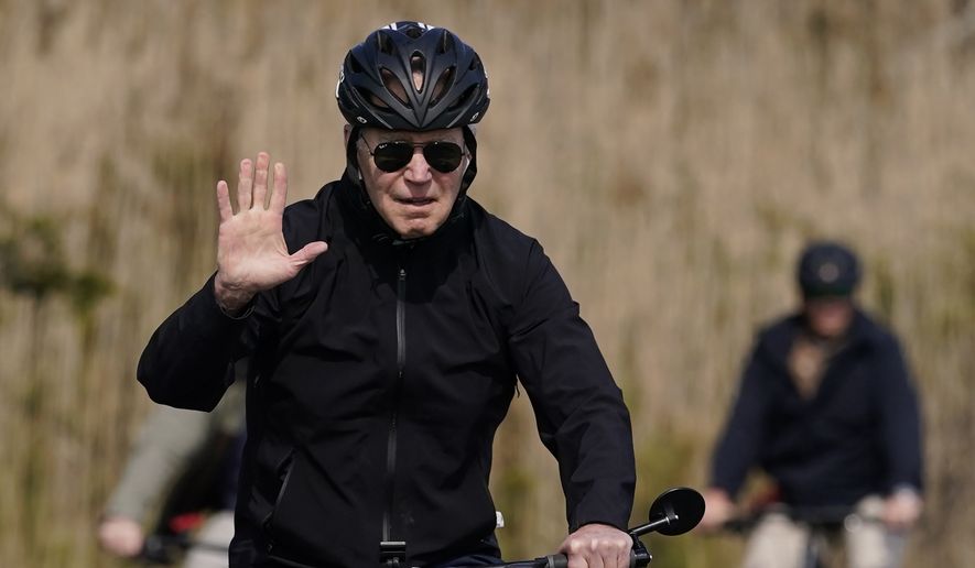 President Joe Biden waves as he rides a bicycle in Gordon&#x27;s Pond State Park in Rehoboth Beach, Del., Sunday, March 20, 2022. (AP Photo/Carolyn Kaster)