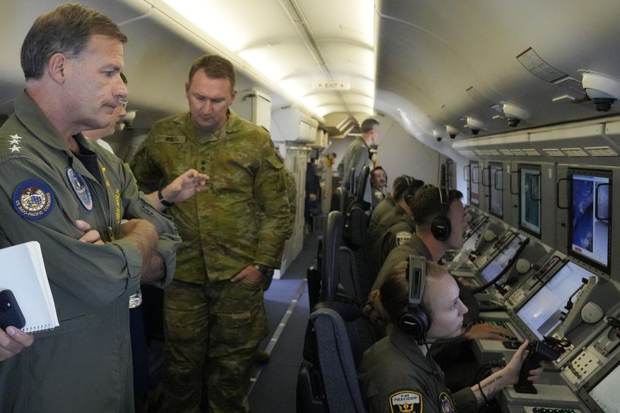 Admiral John C. Aquilino, left, Commander of the U.S. Indo-Pacific Command (INDOPACOM), looks at videos of Chinese structures and buildings on board a US P-8A Poseidon reconaisance plane flying at the Spratlys group of islands in the South China Sea on Sunday March 20, 2022. A U.S. Navy plane carrying a top American military commander was threatened repeatedly by radio on Sunday to leave the airspace over Chinese-occupied island garrisons in the disputed South China Sea, but the aircraft pressed on defiantly with its reconnaissance in brief but tense standoffs witnessed by two Associated Press journalists invited onboard. (AP Photo/Aaron Favila)