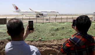 Residents watch as a China Eastern passenger jet prepares to take off on a test flight from the new Beijing Daxing International Airport on Monday, May 13, 2019. State media are reporting a Chinese airliner from China Eastern with 133 people on board crashed in the southern province of Guangxi on Monday, sparking a mountainside fire. (AP Photo/Ng Han Guan, File)