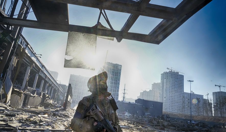 A Ukrainian soldier stands on the ruins after Russian shelling of a shopping center, in Kyiv, Ukraine, Monday, March 21, 2022. At least eight people were killed in the attack. (AP Photo/Efrem Lukatsky)