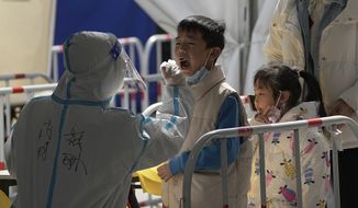 A health worker in protective suit takes a throat swab sample from a child at a coronavirus testing site, Monday, March 21, 2022, in Beijing, China. Disney Co. closed its Shanghai theme park Monday as Chinese authorities tried to control the city&#39;s biggest coronavirus flareup in two years, while the southern business center of Shenzhen allowed shops and offices to reopen after a weeklong closure. (AP Photo/Andy Wong)