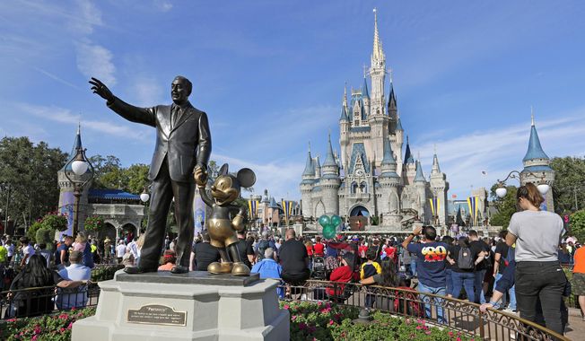 A statue of Walt Disney with Micky Mouse stands near the Cinderella Castle at the Magic Kingdom at Walt Disney World in Lake Buena Vista, Fla. on Jan. 9, 2019. With some workers across the U.S. threatening a walkout Tuesday, March 22, 2022, The Walt Disney Co. finds itself in a balancing act between the expectations of a diverse workforce and demands from an increasingly polarized, politicized marketplace. (AP Photo/John Raoux, File)