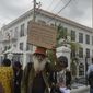 People protest to demand an apology and slavery reparations during a visit to the former British colony by the Duke and Duchess of Cambridge, Prince William and Kate, in Kingston, Jamaica, Tuesday, March 22, 2022. The two-day visit to Jamaica is part of a larger trip to the Caribbean region encouraged by Queen Elizabeth II as some countries debate cutting ties with the monarchy like Barbados did late last year. (AP Photo/Collin Reid)