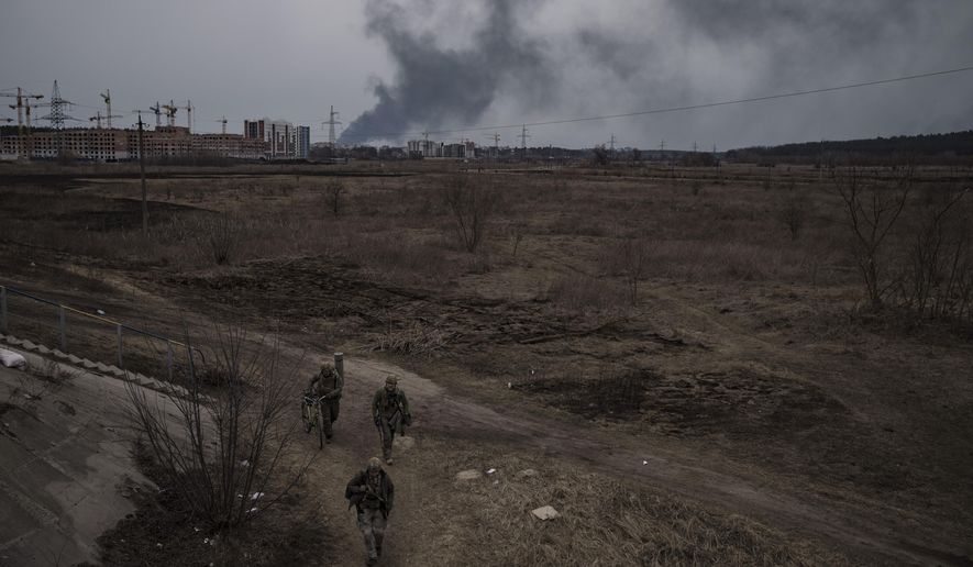 Soldiers walk on a path as smoke billows from the town of Irpin, on the outskirts of Kyiv, Ukraine, Saturday, March 12, 2022. (AP Photo/Felipe Dana)