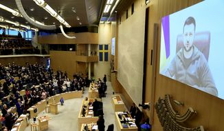 Ukraine&#x27;s President Volodymyr Zelenskyy receives a standing ovation as he adresses the Sweden&#x27;s parliament via video link, in Stockholm, Thursday, March 24, 2022. Zelenskyy has called on people worldwide to gather in public to show support for his embattled country as he prepared to address U.S. President Joe Biden and other NATO leaders gathered in Brussels on the one-month anniversary of the Russian invasion. (Paul Wennerholm/TT News Agency via AP)
