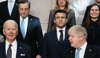 British Prime Minister Boris Johnson, front right, looks toward U.S. President Joe Biden, front left, at a group photo during an extraordinary NATO summit at NATO headquarters in Brussels, Thursday, March 24, 2022. As the war in Ukraine grinds into a second month, Biden and Western allies are gathering to chart a path to ramp up pressure on Russian President Vladimir Putin while tending to the economic and security fallout that&#x27;s spreading across Europe and the world. (AP Photo/Thibault Camus)