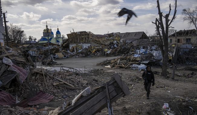 A journalist walks amid the destruction after a Russian attack in Byshiv, in the outskirts of Kyiv, Ukraine, Sunday, March 27, 2022. Ukrainian President Volodymyr Zelenskyy accused the West of lacking courage as his country fights to stave off Russia&#x27;s invading troops, making an exasperated plea for fighter jets and tanks to sustain a defense in a conflict that has ground into a war of attrition. (AP Photo/Rodrigo Abd)