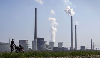 A mother pushes a stroller in front of the Scholven coal fired power station, owned by Uniper, in Gelsenkirchen, Germany, Monday, March 28, 2022. The power plant is being rebuilt from coal to a combined cycle gas turbine plant. With Germany&#39;s energy dependence on Russia&#39;s gas, oil and coal, the planned coal phase-out to fight climate change is discussed to be postponed. (AP Photo/Martin Meissner)