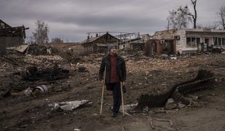A resident stands next to parts of a destroyed Russian tank in the town of Trostsyanets, Ukraine, Monday, March 28, 2022. Trostsyanets was recently retaken by Ukrainian forces after being held by Russians since the early days of the war. (AP Photo/Felipe Dana)