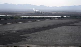 A dried up portion of the Salton Sea stretches out with a geothermal power plant in the distance in Niland, Calif., Thursday, July 15, 2021. Demand for electric vehicles has shifted investments into high gear to extract lithium from geothermal wastewater around the rapidly shrinking body of water. The ultralight metal is critical to rechargeable batteries. (AP Photo/Marcio Jose Sanchez, File)